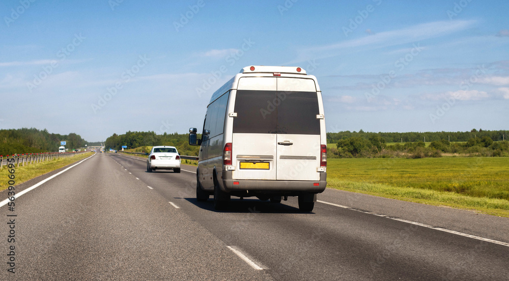 Passenger minibus moves along the motorway in summer against the blue sky. Passenger transportation business concept. Intercity traffic. Copy space for text