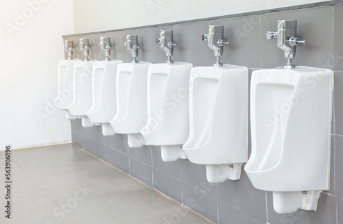 Men's room with white porcelain urinals in line. Modern clean public toilets with tiles. Comfort male toilet urinal concept. photo