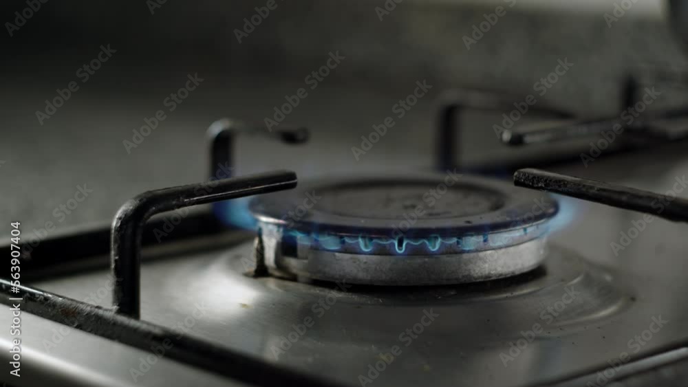 close up view of old gas stove, fire starts to burn and kettle or pot is placed on burner