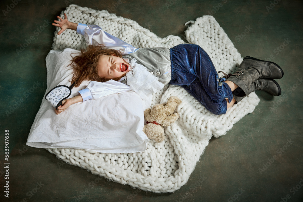 Obraz premium Happy morning, excited wake up. Ariel view of cute little girl in clothes sleeping on white blanket. Concept of napping day, dreams, happy childhood.