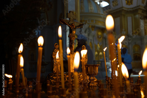 Cross with crucifix in focus, lit wax candles, funeral service, prayers for salvation of soul. Memorial service, an Orthodox church. Concept of Christian religion.