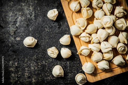 Raw homemade dumplings on a wooden cutting board.  © Artem Shadrin