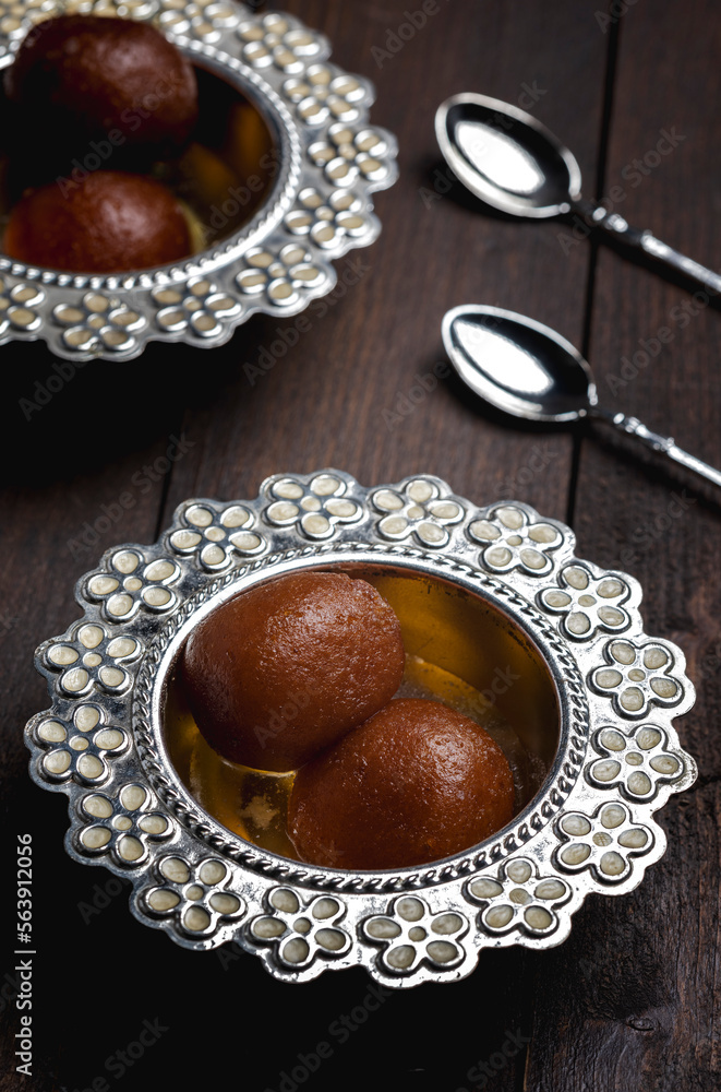 Indian traditional sweet dessert gulab jamun is a soft and fluffy deep fried ball soaked in sugar syrup and served in bowl Indian traditional sweet dessert gulab jamun is a soft and fluffy deep fried ball soaked in sugar syrup and served in bowl