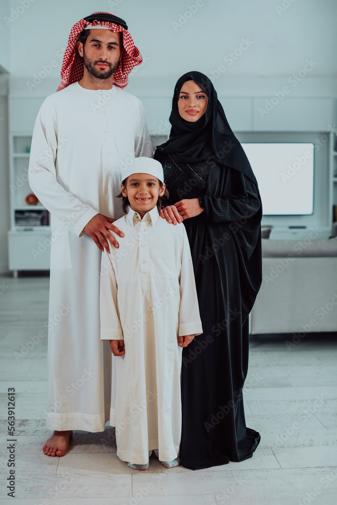 portrait of young happy arabian muslim family couple with son in traditional clothes spending time together during the month of Ramadan at home