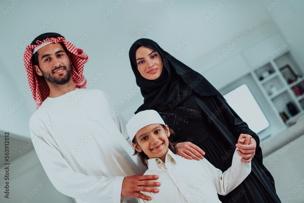 portrait of young happy arabian muslim family couple with son in traditional clothes spending time together during the month of Ramadan at home