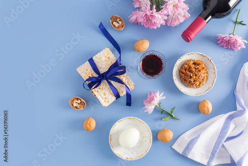 beautiful Passover blue backgroundof Jewish Passover. top view of a bottle of red kosher wine, glasses of wine, matzah, nuts, egg on a plate. photo