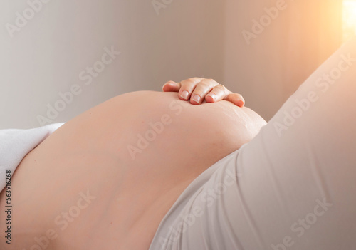 Pregnant girl holds her hand on her stomach. Movement of the baby in the womb during pregnancy. The hiccups of a child. Copy space for text photo