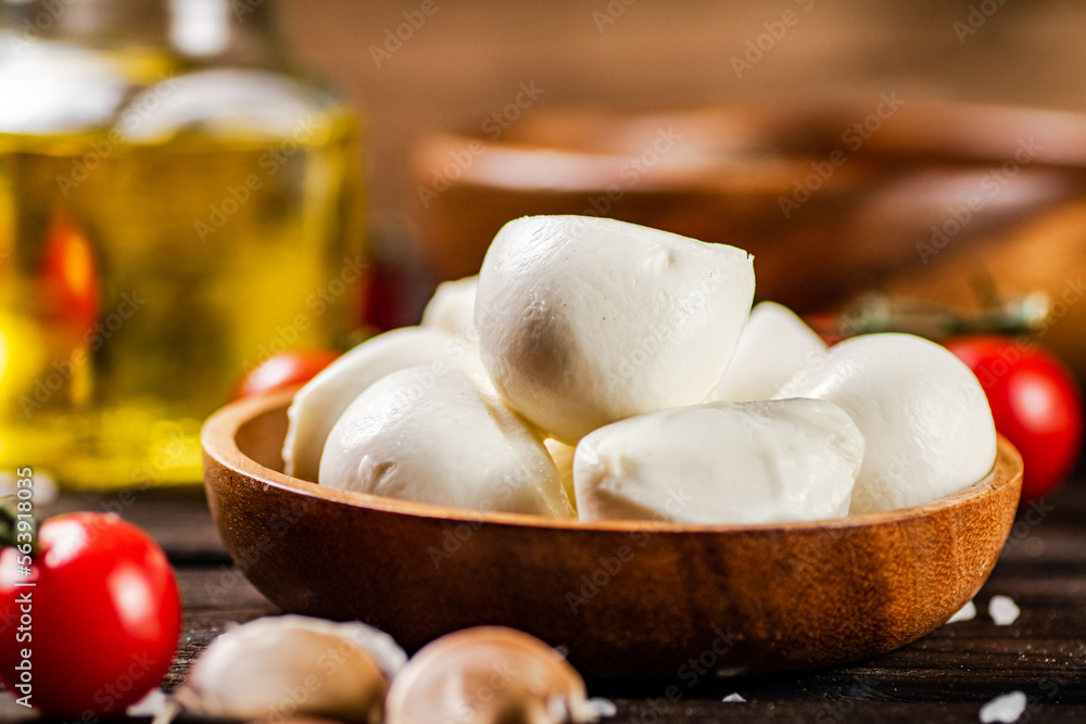 Fototapeta premium Mozzarella cheese on a plate on a table with tomatoes and spices. 