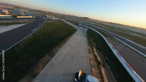 aerial filming of a circuit race on an asphalt circuit, fpv drone, racing cars go fast, time trials, sharp turns