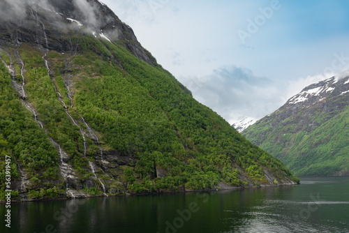 Beautiful landscape with snowy mountain peaks and waterfalls in Geiranger fjord, Norway