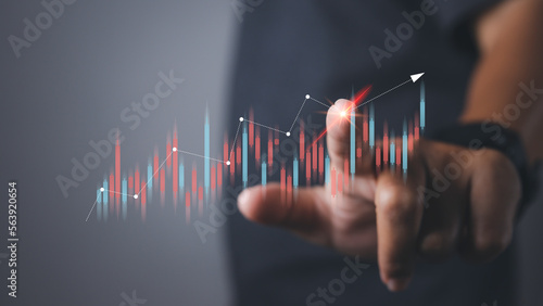 Stock market graph with man touching stock trading screen.