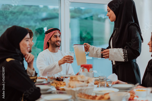  Muslim family having Iftar dinner drinking water to break feast. Eating traditional food during Ramadan feasting month at home. The Islamic Halal Eating and Drinking in modern home 