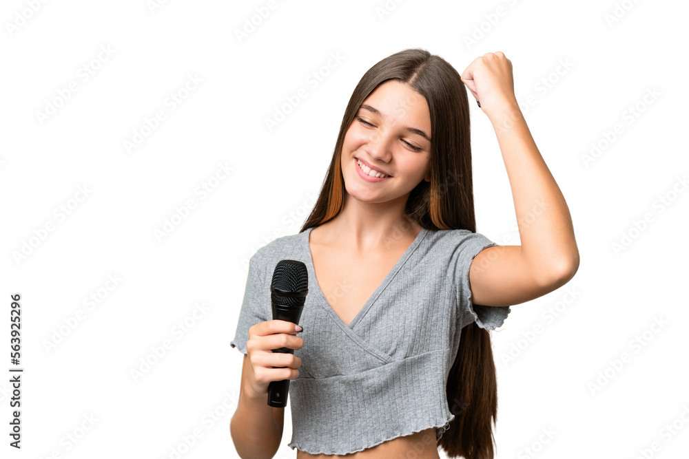 Teenager singer girl picking up a microphone over isolated background celebrating a victory Teenager singer girl picking up a microphone over isolated background celebrating a victory