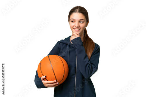 Teenager caucasian girl playing basketball over isolated background looking to the side and smiling