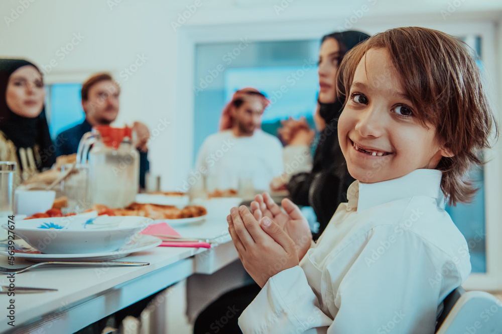 Fototapeta premium A Muslim family praying together, the Muslim prayer after breaking the fast in the Islamic holy month of Ramadan