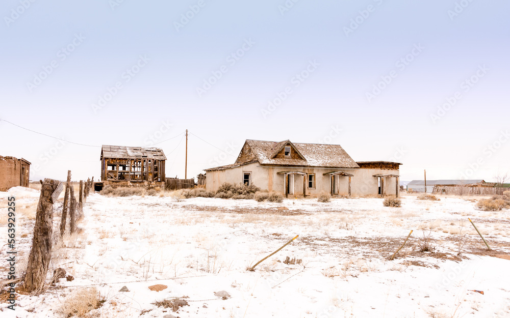 Abandoned adobe in snow, with fence and out building, Costilla, NM