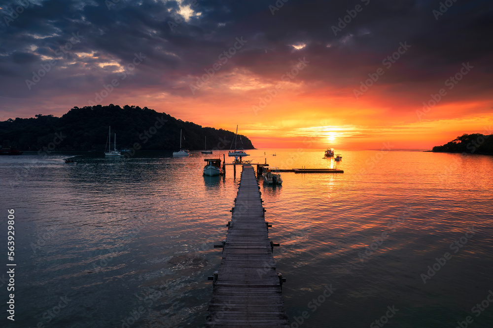 Obraz premium Beautiful sunset over tropical sea and wooden pier, sightseeing boat and tourist enjoying in Koh Kood Island