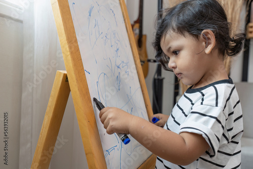 Small boy concentrate use color pen draw the white board alone in the room