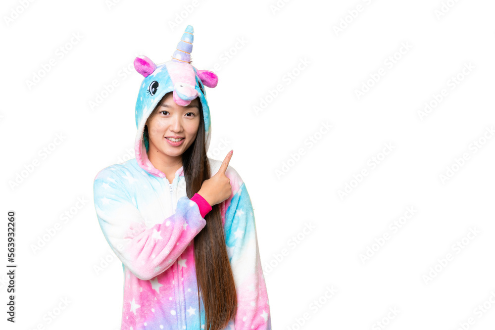 Young Asian woman with unicorn pajamas over isolated chroma key background pointing to the side to present a product