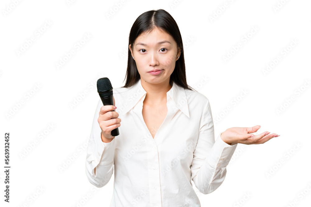 Singer picking up a microphone over isolated chroma key background making doubts gesture while lifting the shoulders Singer picking up a microphone over isolated chroma key background making doubts gesture while lifting the shoulders