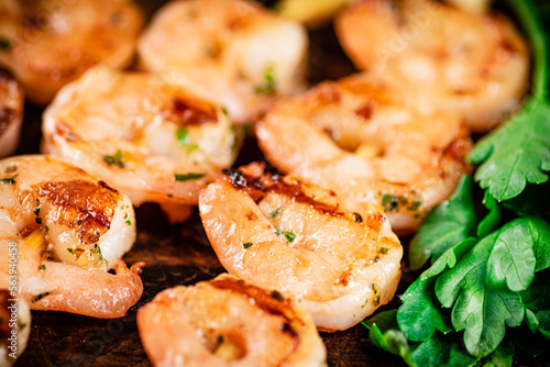 Grilled shrimp with parsley on a wooden background.