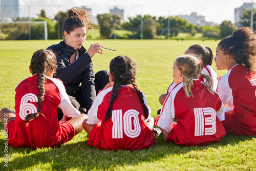 Coaching  exercise or coach with children for soccer strategy  training and team goals in Canada. Team building  teamwork and woman planning group of girl on football field for game  match or workout
