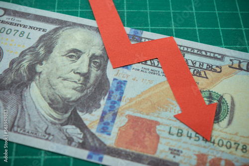 Red graph falling down on US dollar banknote background. The Federal Reserve ( FED ) increase % interest rates to fix inflation crisis. World global economy recession and stagflation concept.