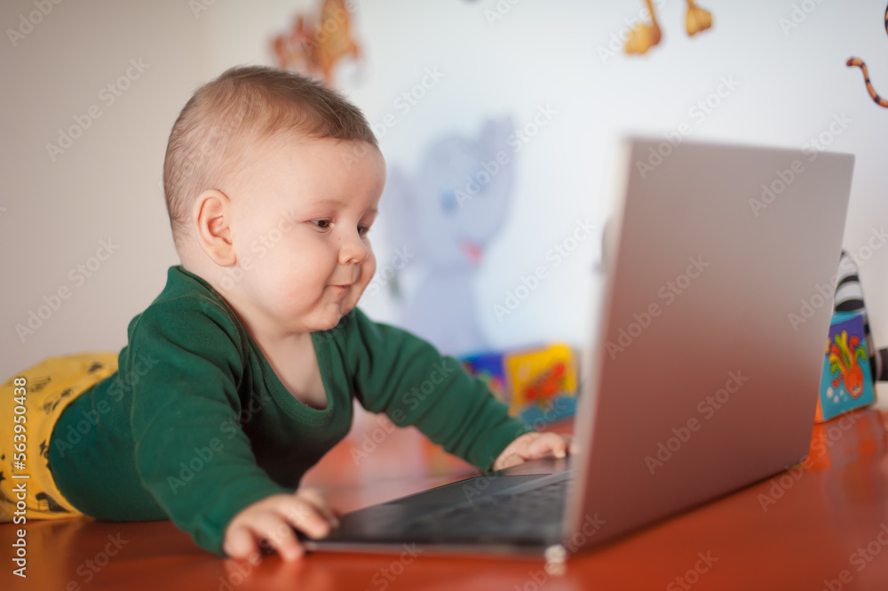 Portrait of baby boy using a laptop computer at his business office - game room. Technology and toys concept. Funny babies Portrait of baby boy using a laptop computer at his business office - game room. Technology and toys concept. Funny babies