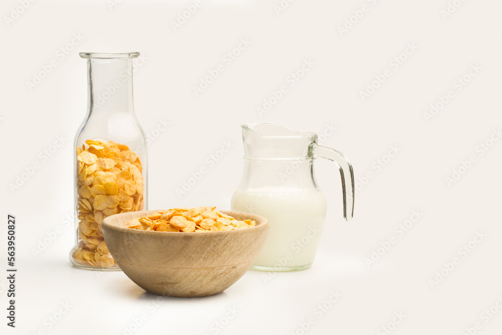 Cuenco con copos de maíz junto a una jarra con leche sobre un fondo blanco liso y aislado. Vista de frente y de cerca. Copy space Cuenco con copos de maíz junto a una jarra con leche sobre un fondo blanco liso y aislado. Vista de frente y de cerca. Copy space