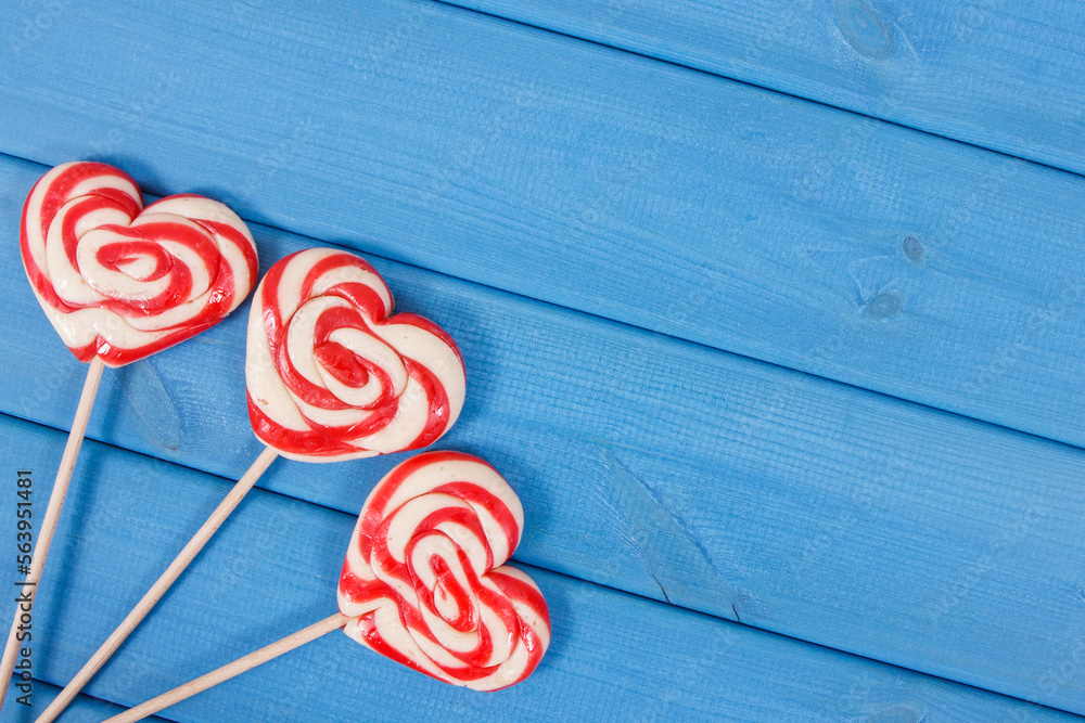 Sweet funny lollipop in shape of heart on blue boards. Surprise for child. Memory of childhood. Place for text Sweet funny lollipop in shape of heart on blue boards. Surprise for child. Memory of childhood. Place for text