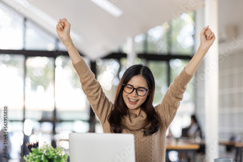 Portrait of Happy Excited young asian woman at workplace office desk, successful Asian female reading good news technology online, employee freelance finance concepts.