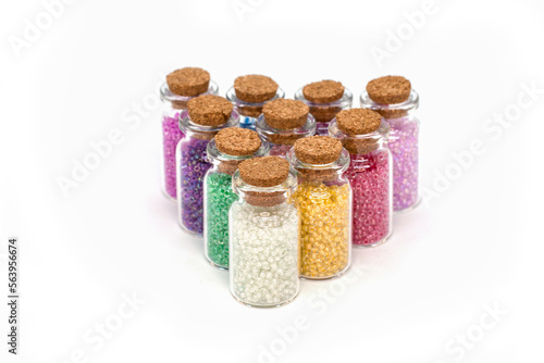 Glass jars with a cork for storing beads. Color sorted beads.
