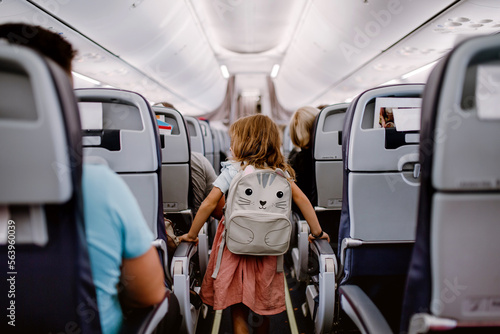 Rear view of little girl standing in aisle in the plane.