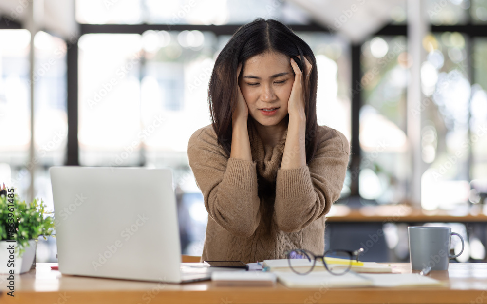 Tired Young freelance asian business woman with headache at office, feeling sick at work, Sad, unhappy, Worried, Depression, or employee life stress concept. Tired Young freelance asian business woman with headache at office, feeling sick at work, Sad, unhappy, Worried, Depression, or employee life stress concept.