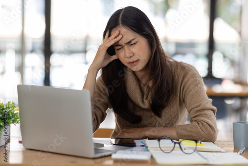 Tired Young freelance asian business woman with headache at office, feeling sick at work, Sad, unhappy, Worried, Depression, or employee life stress concept.