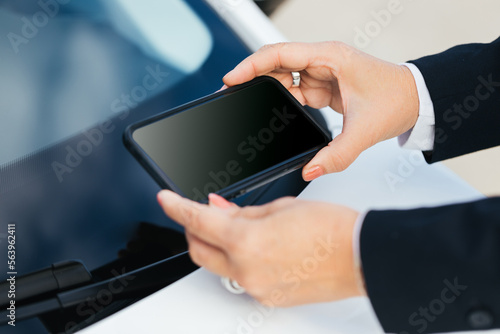 An elderly person taking a photo of the VIN number on the car behind the windshield for an insurance company photo