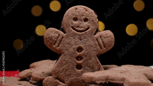 Gingerbread man cookie with Christmas tree flickering lights bokeh in background. Xmas Holiday Season winter composition.