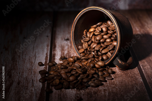 Coffee beans spilled out of the cup on the table in the kitchen 