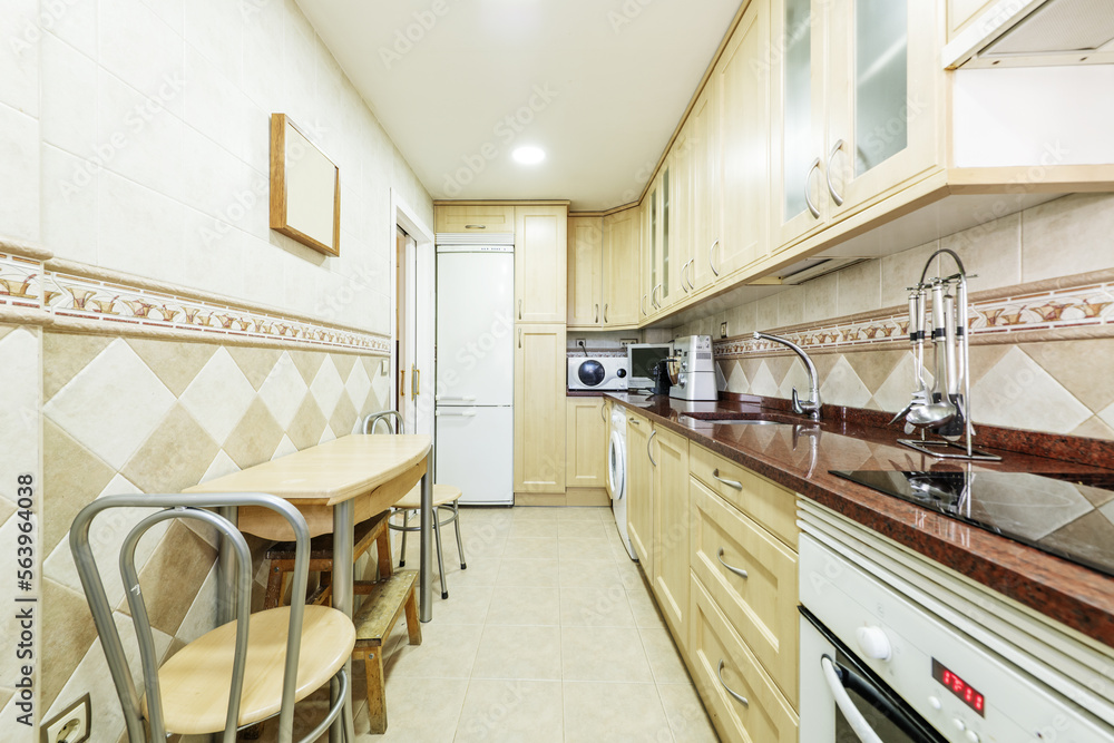 Kitchen furnished in beech-colored wood with polished red marble countertop and folding table with matching chairs Kitchen furnished in beech-colored wood with polished red marble countertop and folding table with matching chairs