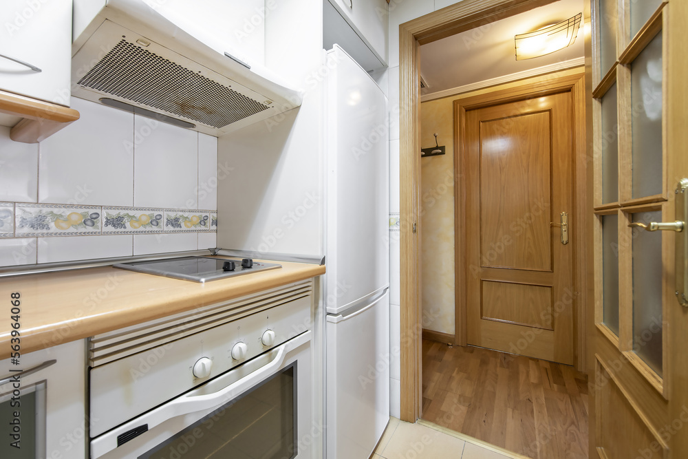 Fototapeta premium Small kitchen with white appliances and oak access door with beveled glass
