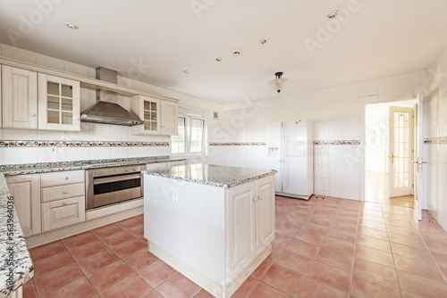 Large kitchen room with old-fashioned white cabinets with polished granite countertops and matching island