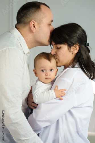 young parents kiss their little baby