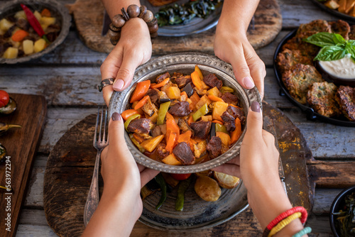 Meat stew with vegetables at the hands of two women. Orman kebabı .