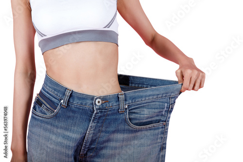 Woman shows weight loss. Slim woman is happy to show her big old jeans. Fit woman in oversize blue jeans on pastel pink background. Diet and weight loss concept.