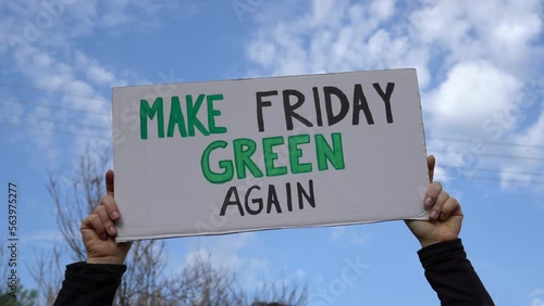 Woman holding sign with slogan Make Friday Green Again. Protester with placard at zero waste protest rally. Ecology environmental issues, demonstration against Black Friday Sale, overproduction.