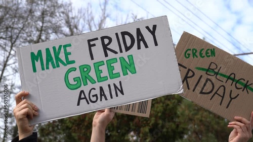Protesters holding signs with slogans Make Friday Green Again, Green Black Friday and Stop Black Friday. People with placards at zero waste protest rally. Ecology environmental issues demonstration.