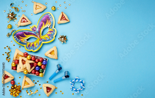 Purim Hamantaschen Cookies, Carnival Mask, Noisemaker, Sweet Candies on Blue Background.