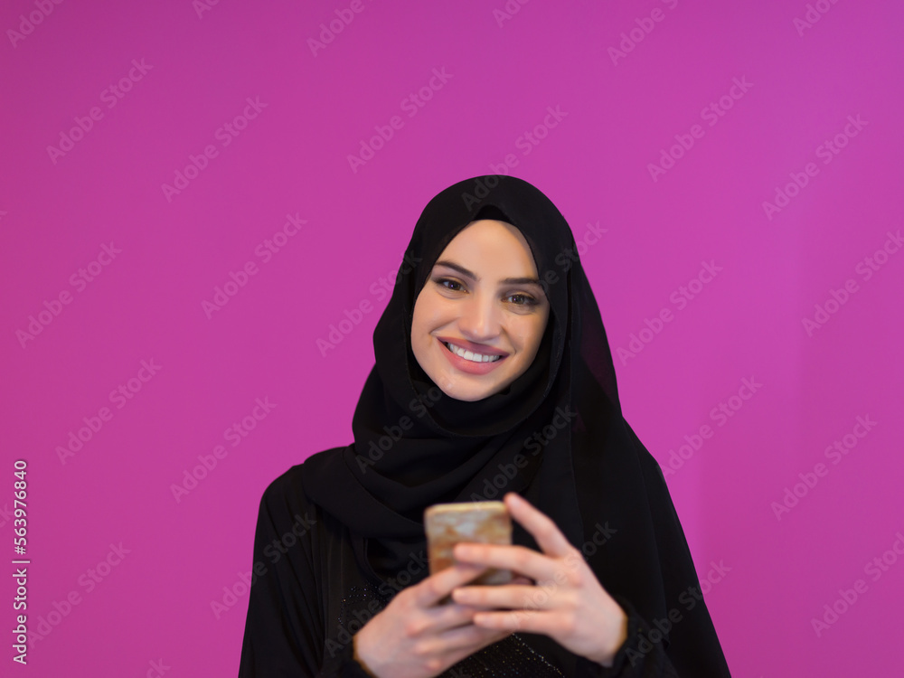 Young modern muslim business woman using smartphone wearing hijab clothes isolated on pink background Young modern muslim business woman using smartphone wearing hijab clothes isolated on pink background