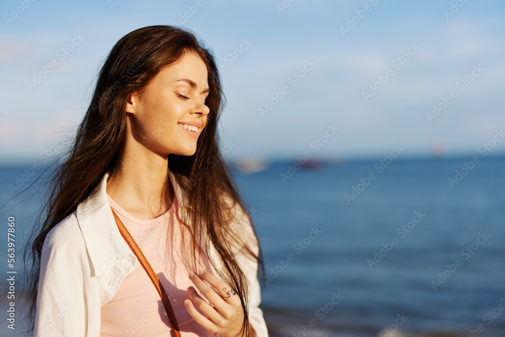Woman portrait smile with teeth freedom on vacation walking on the beach by the ocean in Bali sunset, happy travel and relaxation, sunset light, flying hair, skin care concept in the sun