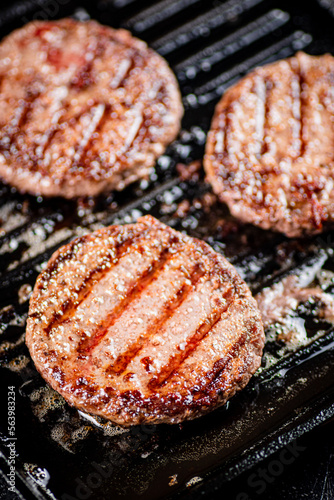 Cooking a delicious grilled burger on a pan with oil bubbles.